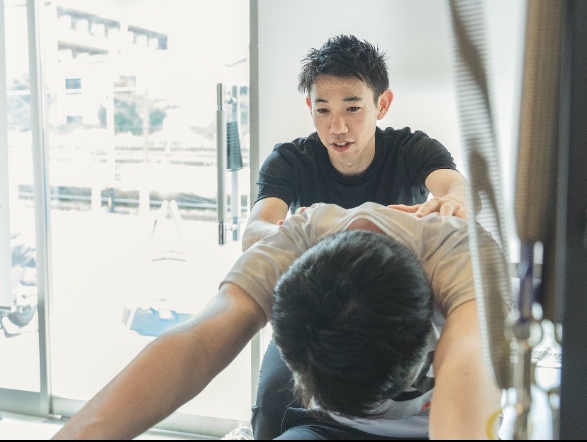 長岡京ピラティス・トレーニング&鍼灸院のトレーナーが、背中に手を添えてピラティスを指導する様子
